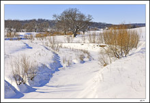 Snow-Softened Banks Along The Stilled Stream